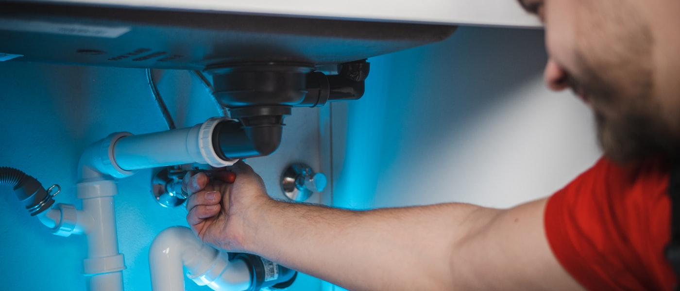 Plumber repairing pipework under a sink
